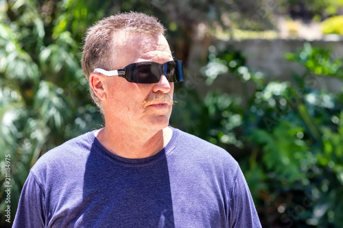 Senior male weats protective sunglasses in bright sun after optometrist visit to protect his eyes