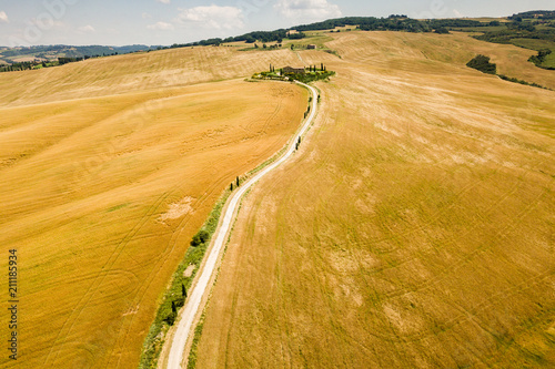 Typical countryside summer landscape in Tuscany, Italy. Road through a wheat field. Aerial view by drone.