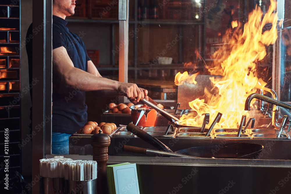 Cooking process in an Asian restaurant. Cook is fry vegetables with ...