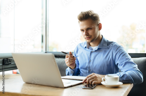 Young man drawing template for the web site associated with digital marketing, current trends and tendencies of UX / UI design. Businessman who rules his company remotely, like a freelancer photo