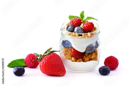 Healthy berry fruit parfait in a mason jar with scattered fruit isolated on a white background