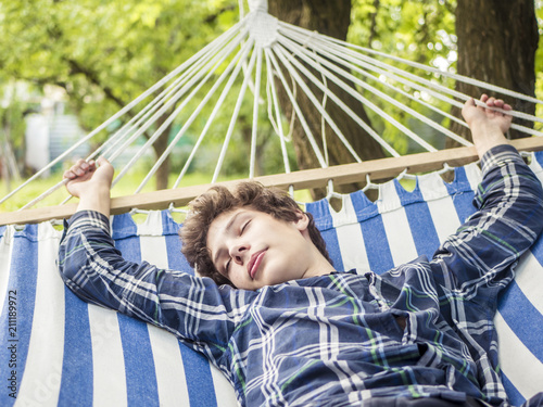 young happy teenager smiling and laughing lying in hammock in tropical forest