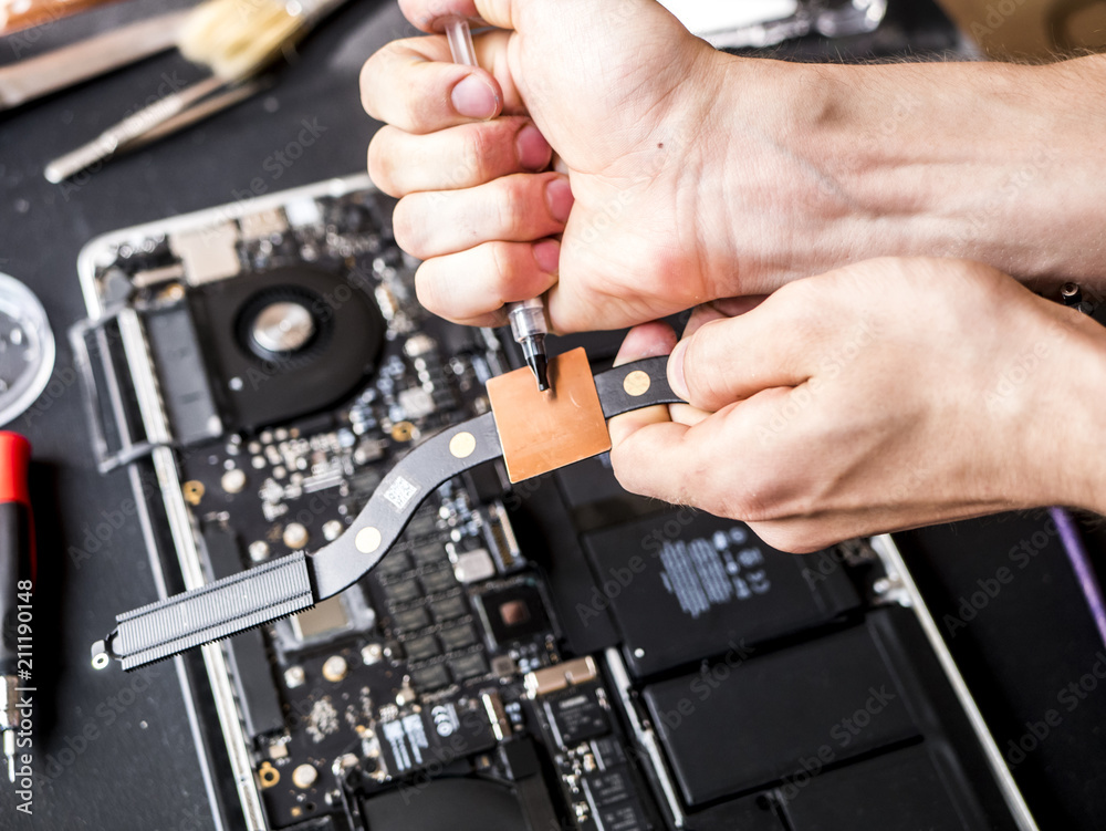 hands with thermal paste applying it to the computer laptop chip
