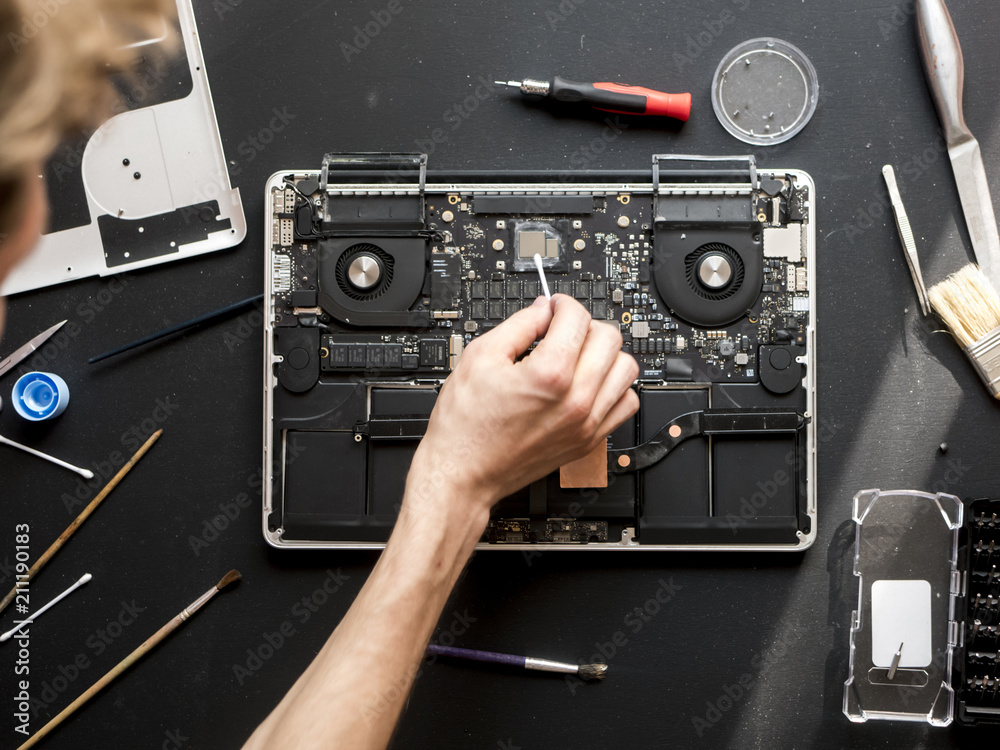 overhead computer master repairing the laptop on dark table with tools