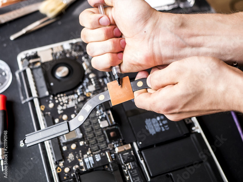 hands with thermal paste applying it to the computer laptop chip