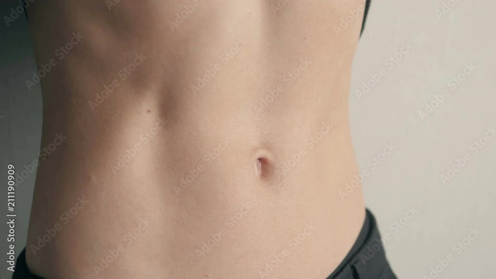 Close-up of the abdominal muscles young athlete on gray background Close-up of the abdominal muscles young athlete on gray background