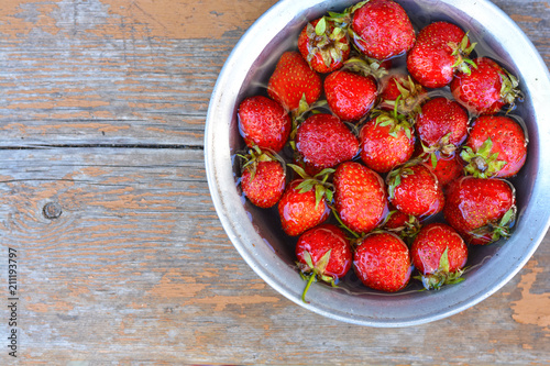 A bowl of strawberries, ripe berries in the garden on the grass