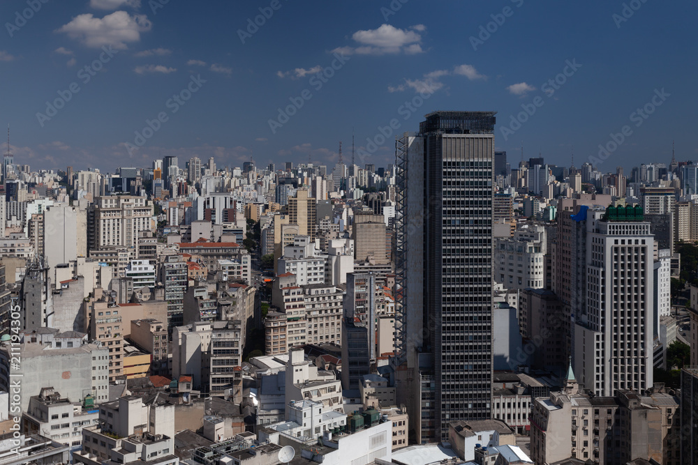 General cityscape with buildings as far as you can see under blue sky