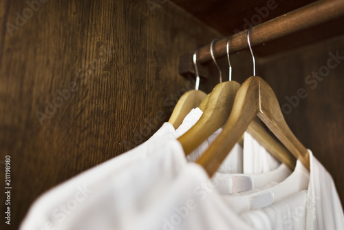White clothes hanging in a wardrobe