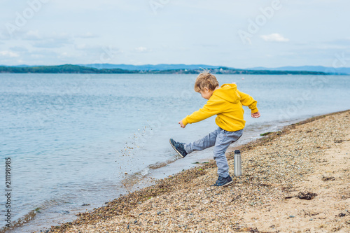 Young boy throwing stones in sea water photo