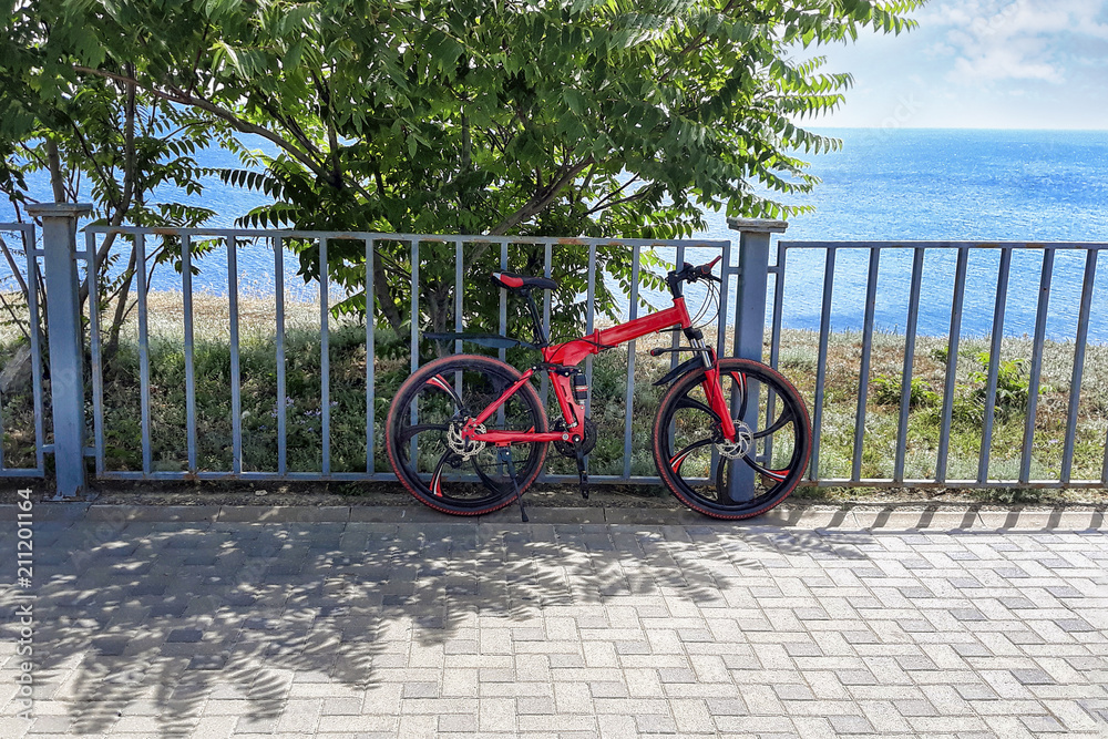 Bicycle at fence in background of sea and trees on hot summer spring day.