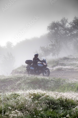 man riding a motorbike on foggy road in early morning