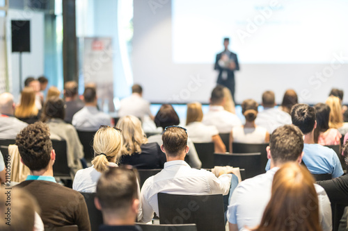 Speaker giving a talk in conference hall at business event. Audience at the conference hall. Business and Entrepreneurship concept. Focus on unrecognizable people in audience. photo