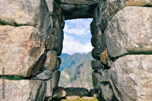 Peeking through a rock window at the Andes Mountains on top of Machu Picchu, Peru.