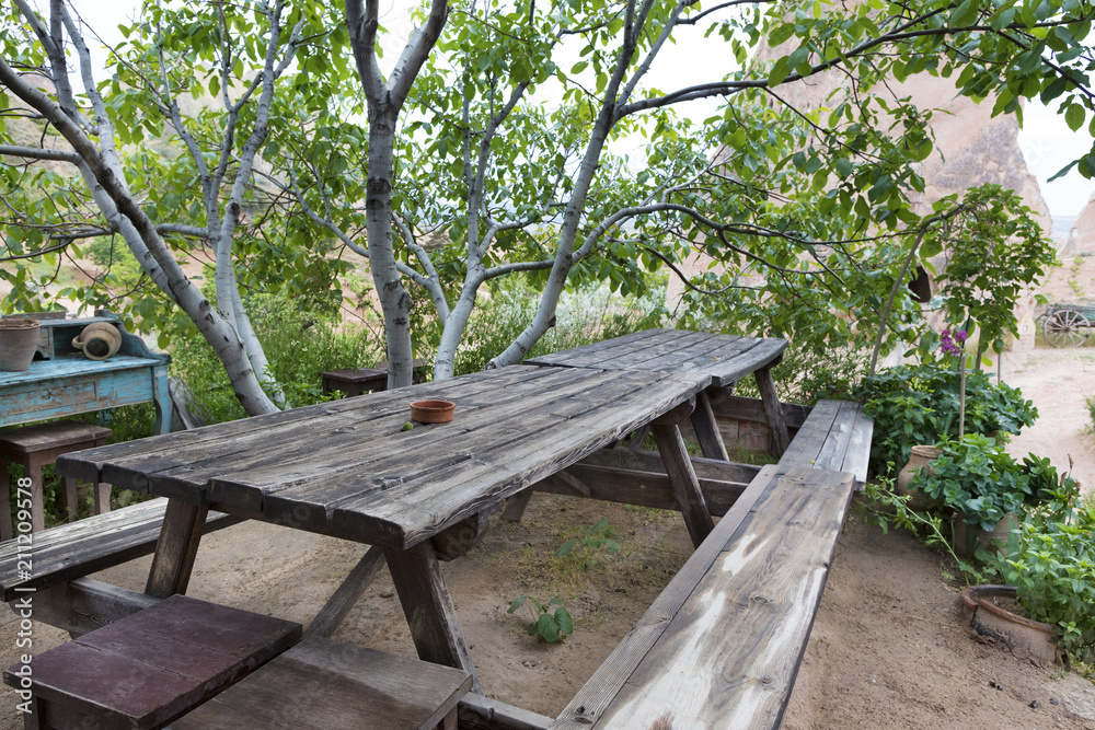 Old, weathered wooden table and benches in the garden under the tree Old, weathered wooden table and benches in the garden under the tree