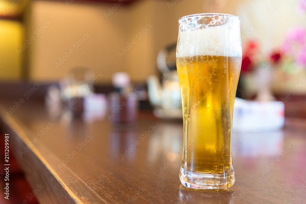 Full cold beer in a glass at bar counter Full cold beer in a glass at bar counter