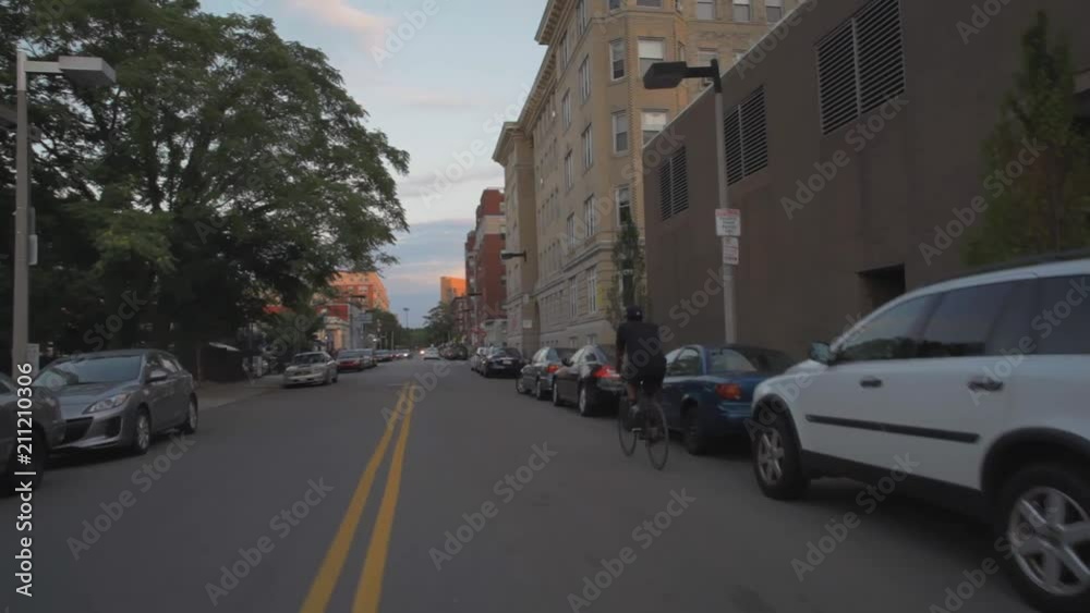 Camera floats by rider on city street with parked cars in background Camera floats by rider on city street with parked cars in background