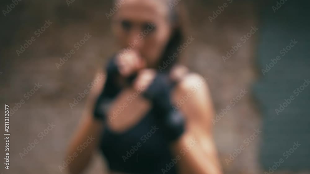 Beautiful Mixed Race Kickboxing woman training under rain outdoors. Fierce strength fit body kickboxer series