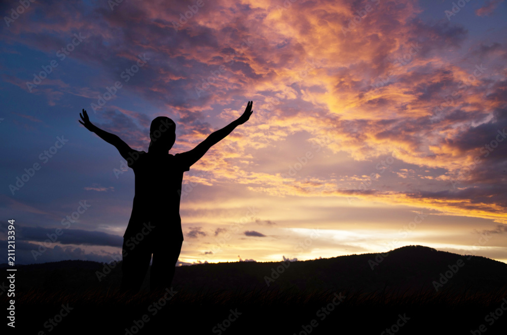 Silhouette of woman praying over beautiful sky background