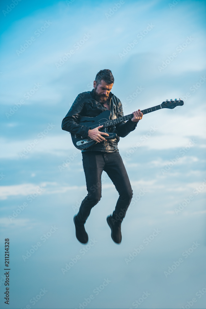 Naklejka premium Man playing guitar at sky background. Freedom and creativity concept