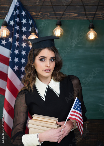 Group four happy people having waving American flag. American flag blackboard. Education university and school system in The United States of America. Concept with US flag and graduation hat symbol