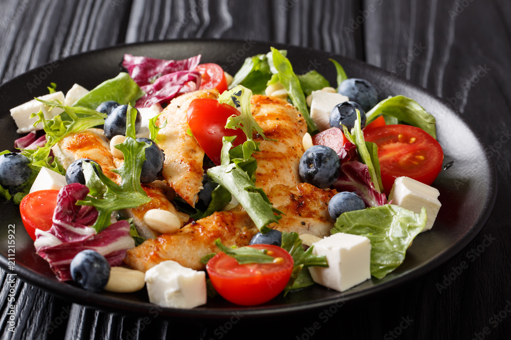 Low-calorie salad with blueberries, feta, chicken, nuts, tomatoes and lettuce close-up. horizontal