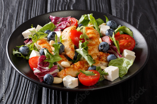 Fresh homemade appetizer salad with blueberries, feta cheese, chicken, nuts, tomatoes and lettuce close-up. horizontal