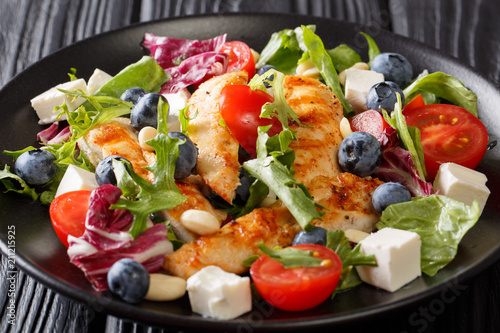 Summer grilled chicken salad, blueberries, feta, nuts, tomatoes and mix lettuce close-up. horizontal