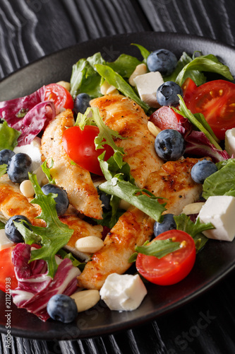 Fresh grilled chicken salad with blueberries, cheese, nuts, tomatoes and lettuce close-up. vertical