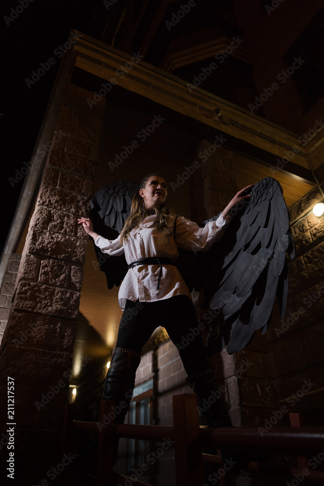 Obraz premium Woman with black wings in night city