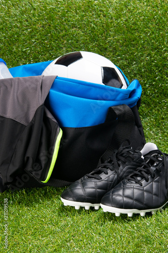 soccer ball  in a sports bag and a T-shirt  a water bottle  black boots  on a grass background