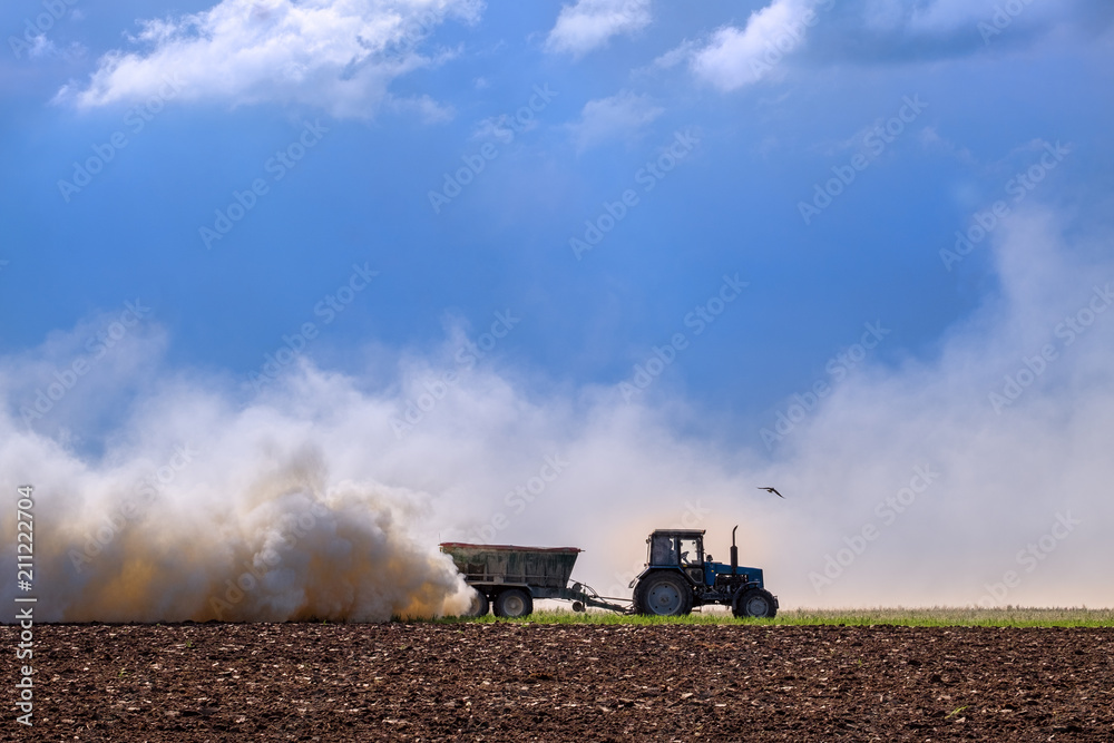Obraz premium tractor pulling plow, throwing dust up in the air. Tractor machine Cultivation field during agricultural works