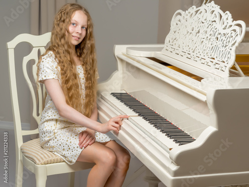 The girl is at the white grand piano.