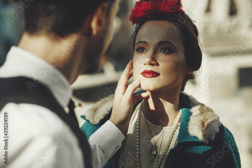 Beautiful woman dressed in 30's style stands on the street and looks at her man with love photo