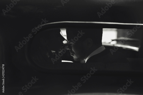 Dreamy picture of a kissing couple dressed in 30's style and sitting in the car © IVASHstudio