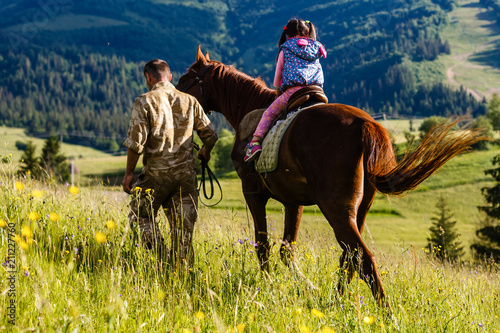 Dad teaches his daughter to ride a horse. Lesson with Riding Instructor.