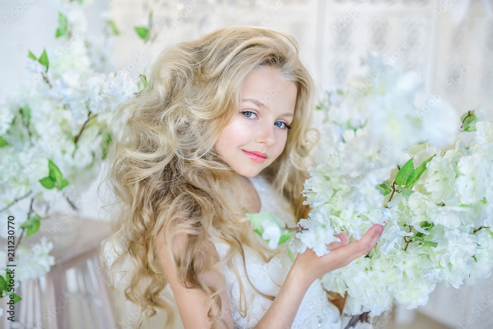 Naklejka premium Beautiful little girl with long blonde hair poses in the studio