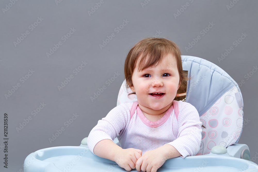 Adorable toddler girl is having fun while eating on greyish background Adorable toddler girl is having fun while eating on greyish background
