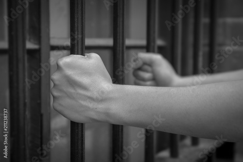 lady hand hold jail bar  in concept of human trafficking and crime prisoner in monotone