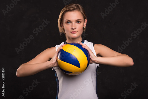 Girl playing volleyball on a dark background