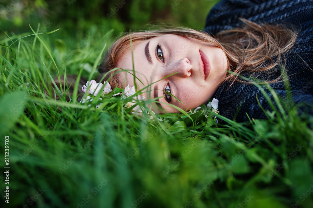 Young brunette girl lying on green grass with branches of blossom tree. Young brunette girl lying on green grass with branches of blossom tree.