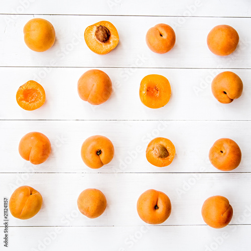 Foto fresh apricot creative pattern in square on white wooden background with leaves
