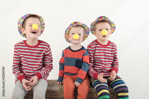 Funny clown children dressed up in costumes and represent the circus. The child is playing at home. The hat is a bowler and a yellow patch on the nose. 1 April. Concept of a fool's day. Copy space.