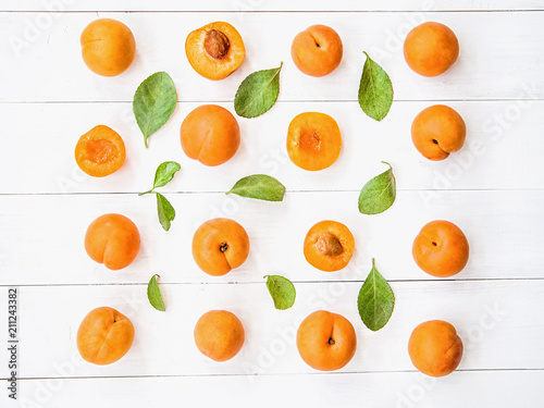 Fotografija fresh apricot creative pattern in square on white wooden background with leaves