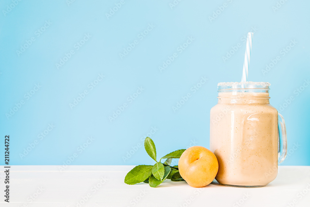 apricot milkshake decorated with fresh apricot and green leaves on white and blue background apricot milkshake decorated with fresh apricot and green leaves on white and blue background