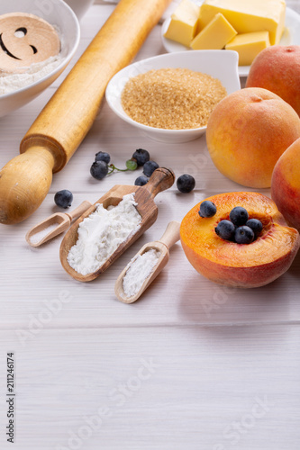 Ingredients for baking fruit pie on white table.
