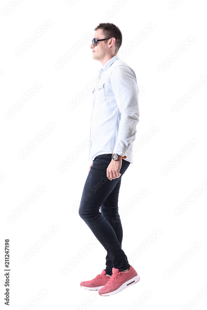 Young elegant adult man with sunglasses walking and looking ahead. Side view. Full body isolated on white background. Young elegant adult man with sunglasses walking and looking ahead. Side view. Full body isolated on white background.