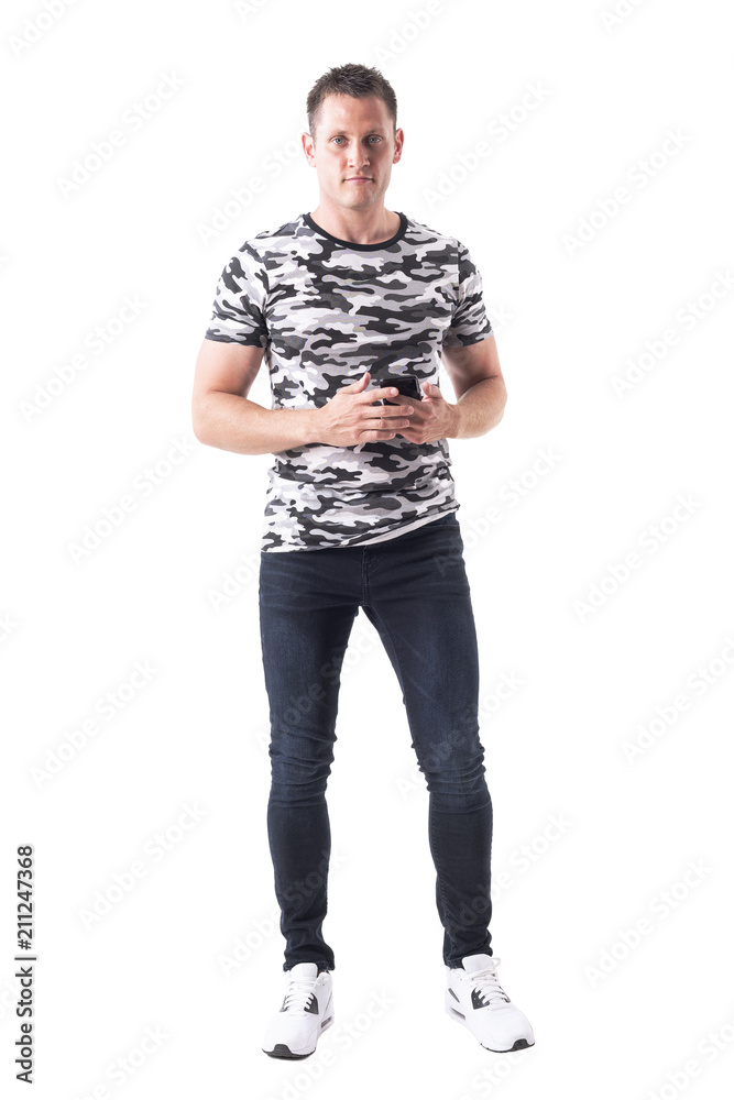 Handsome muscular stylish man in camo shirt holding mobile phone and looking at camera. Full body isolated on white background. Handsome muscular stylish man in camo shirt holding mobile phone and looking at camera. Full body isolated on white background.