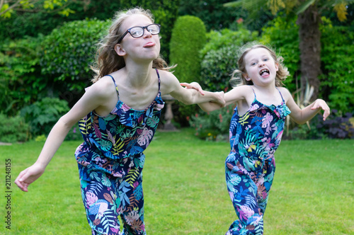 two sisters running pulling faces in the back garden