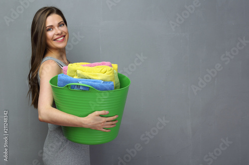 Laundry concept portrait with woman holding basket with towels.